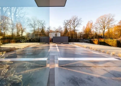 Une terrasse en béton avec des reflets de verre, entourée d'arbres dénudés sous un ciel clair.