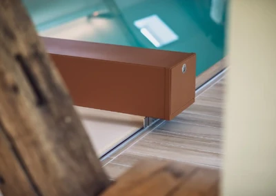 Boîtier rectangulaire marron fixé sur une structure en bois près d'une surface en verre turquoise et un sol en bois clair.