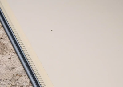 Une bordure en métal sépare une surface en pierre texturée d'un sol beige lisse.