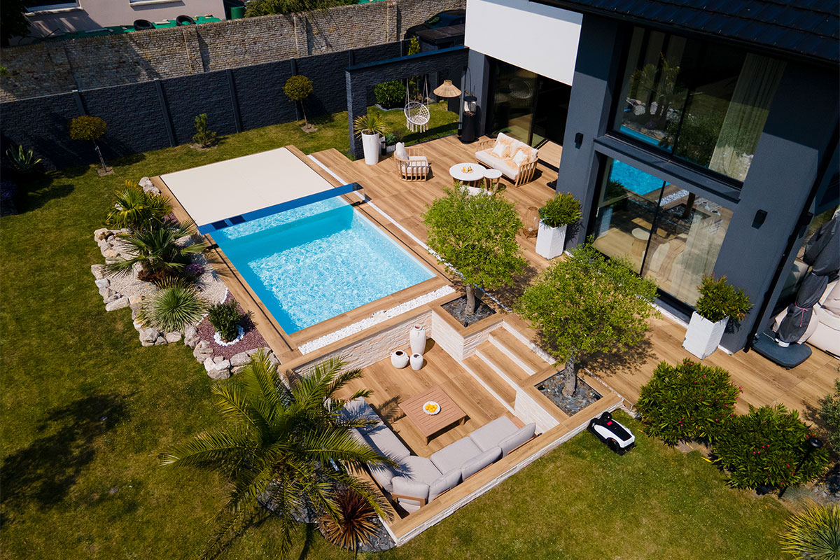 DreamHomeFamily1 Piscine contemporaine partiellement couverte par une Coverseal, entourée d’une terrasse en bois clair et d’un coin lounge élégant.
