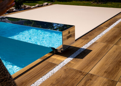 Zoom sur le coffre miroir de la couverture Coverseal, reflétant l’eau turquoise de la piscine et la terrasse environnante.
